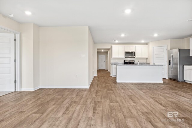 kitchen with an island with sink, white cabinetry, wood-type flooring, and stainless steel appliances