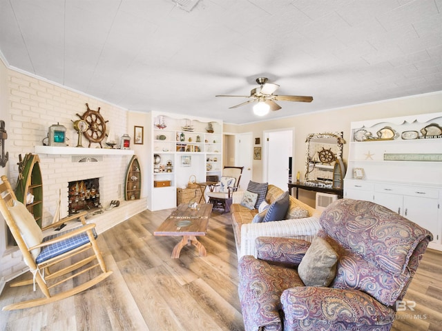 living room with a fireplace, ceiling fan, light wood-type flooring, and crown molding