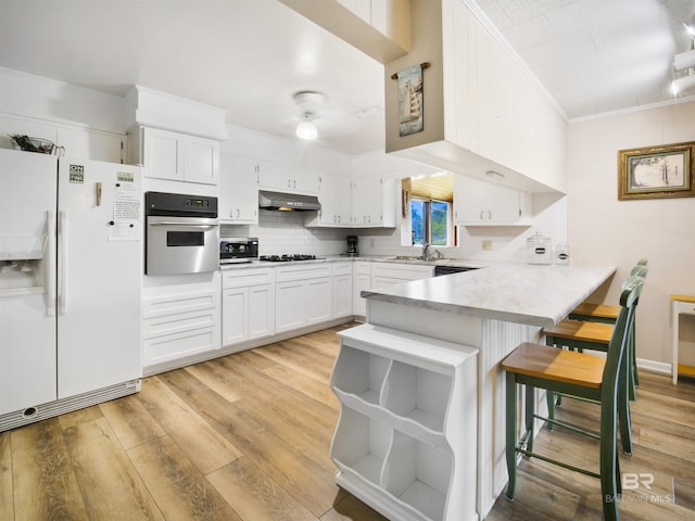 kitchen featuring a kitchen bar, kitchen peninsula, white cabinetry, oven, and white fridge with ice dispenser