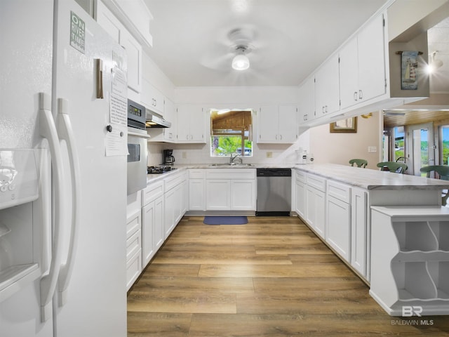 kitchen with white cabinets, appliances with stainless steel finishes, kitchen peninsula, and a wealth of natural light