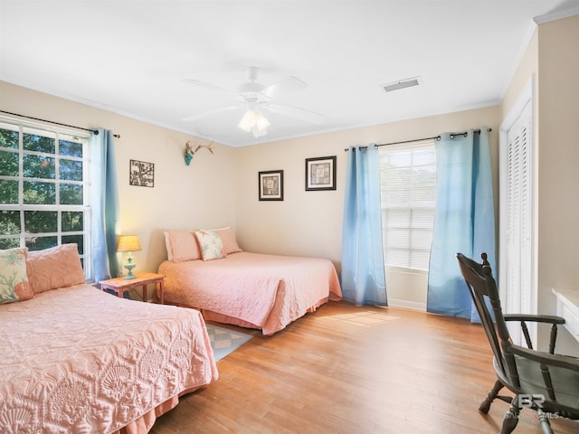 bedroom with ceiling fan, light hardwood / wood-style floors, and ornamental molding