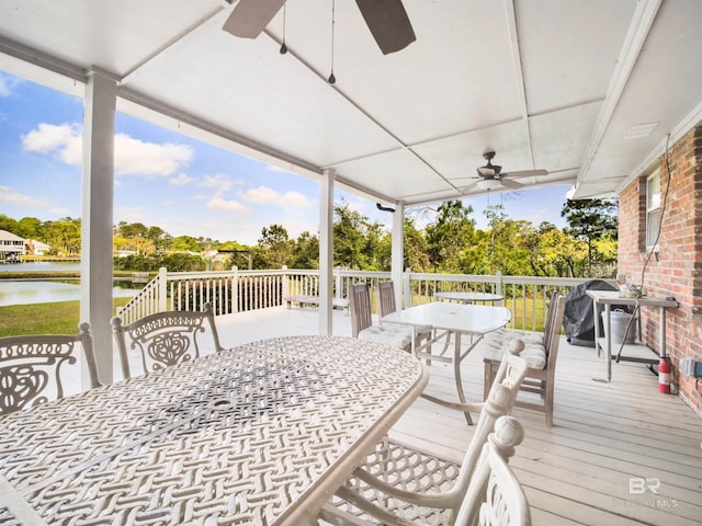 wooden deck featuring grilling area, ceiling fan, and a water view
