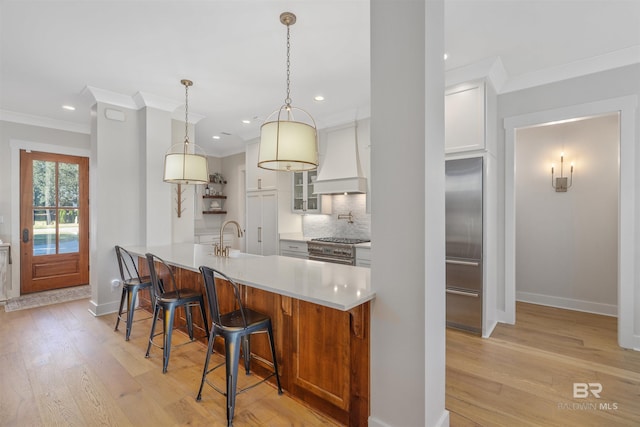 kitchen featuring white cabinetry, tasteful backsplash, high end stainless steel range, custom range hood, and light wood-type flooring