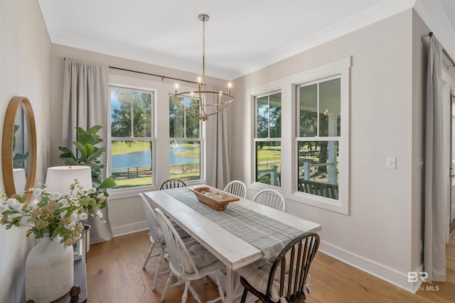 dining room with an inviting chandelier, ornamental molding, and light wood-type flooring