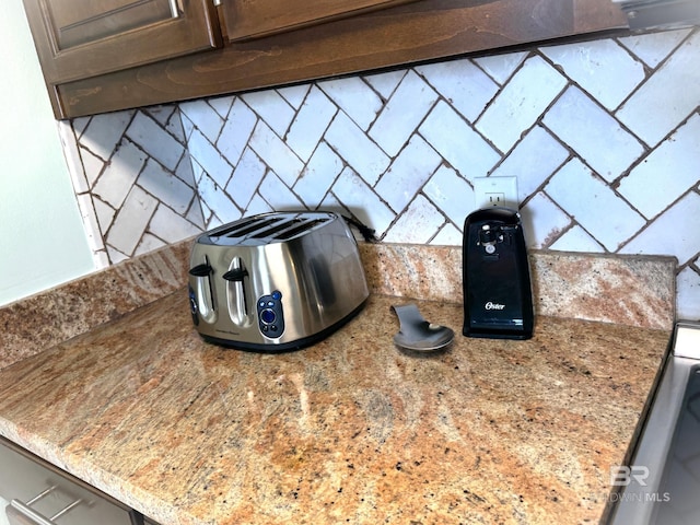 room details featuring dark brown cabinets and light stone countertops