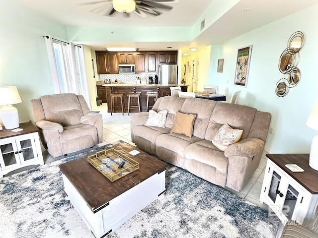 living area featuring light tile patterned floors, visible vents, and ceiling fan