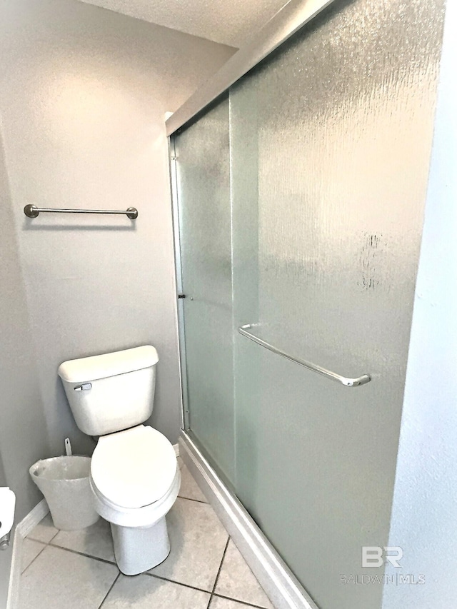 full bathroom with tile patterned floors, a stall shower, and toilet