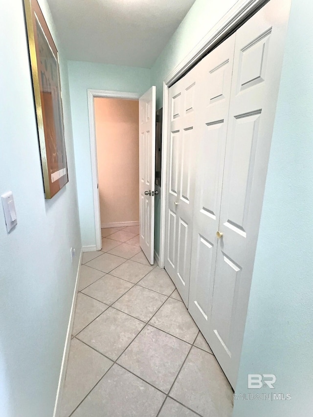 corridor featuring light tile patterned floors and baseboards