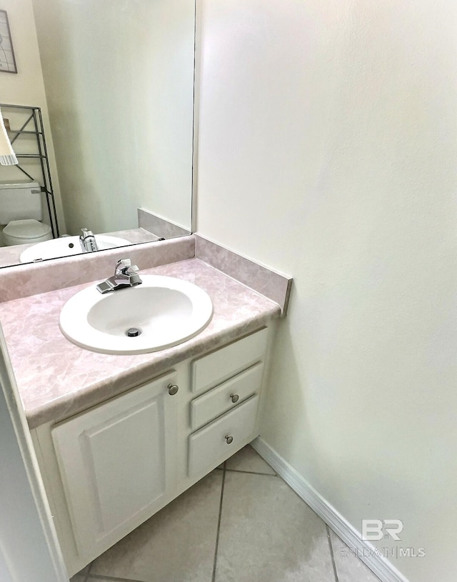 half bath with vanity, tile patterned floors, toilet, and baseboards