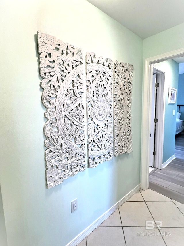 corridor featuring light tile patterned flooring and baseboards