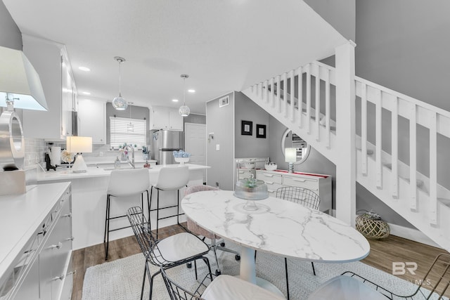 dining space featuring dark wood-type flooring, recessed lighting, visible vents, and stairway