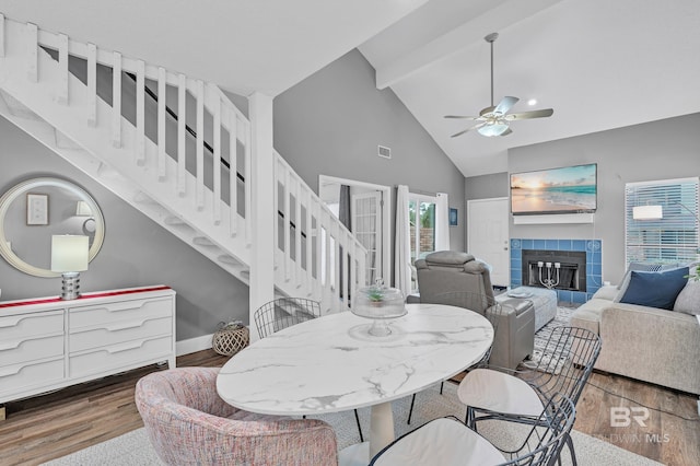 dining area featuring ceiling fan, beam ceiling, a fireplace, wood finished floors, and visible vents