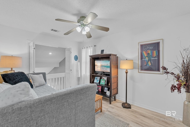 bedroom with visible vents, light wood-style floors, baseboards, a textured ceiling, and a ceiling fan