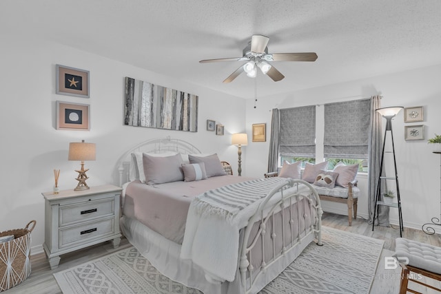 bedroom with baseboards, a textured ceiling, light wood finished floors, and ceiling fan