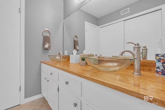 full bath with double vanity, tile patterned floors, visible vents, and a sink