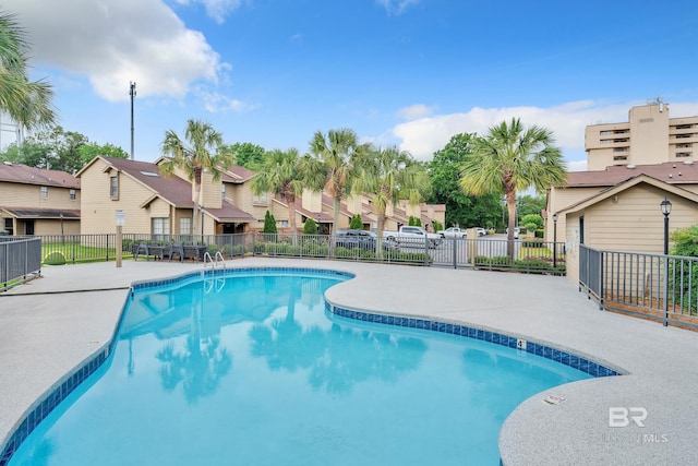 community pool featuring a patio, fence, and a residential view
