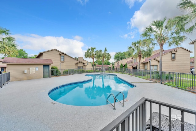 pool featuring a patio, fence, and a residential view