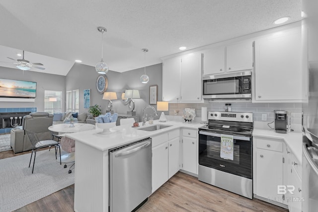 kitchen featuring a ceiling fan, appliances with stainless steel finishes, light wood-type flooring, a sink, and open floor plan