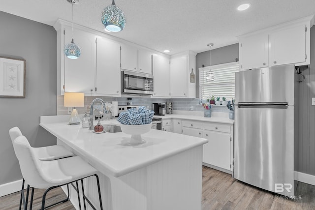 kitchen with white cabinets, a peninsula, tasteful backsplash, and stainless steel appliances