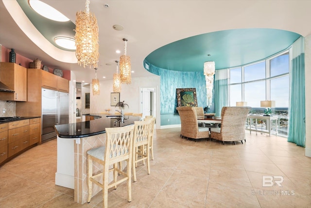 26302 Perdido Beach Blvd Unit D2201, Orange Beach, AL 36561 - kitchen with built in fridge, dark countertops, light tile patterned flooring, black cooktop, and tasteful backsplash