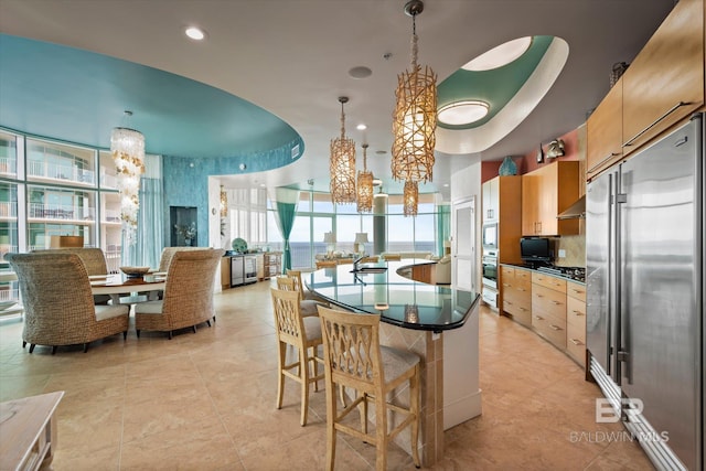 26302 Perdido Beach Blvd Unit D2201, Orange Beach, AL 36561 - kitchen with appliances with stainless steel finishes, dark countertops, a chandelier, light brown cabinetry, and a wall of windows