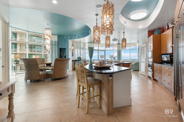 26302 Perdido Beach Blvd Unit D2201, Orange Beach, AL 36561 - kitchen featuring a large island with sink, dark countertops, light tile patterned floors, pendant lighting, and a breakfast bar area