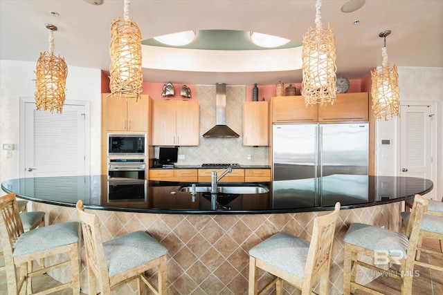 26302 Perdido Beach Blvd Unit D2201, Orange Beach, AL 36561 - kitchen with built in appliances, wall chimney range hood, a sink, light brown cabinetry, and a breakfast bar