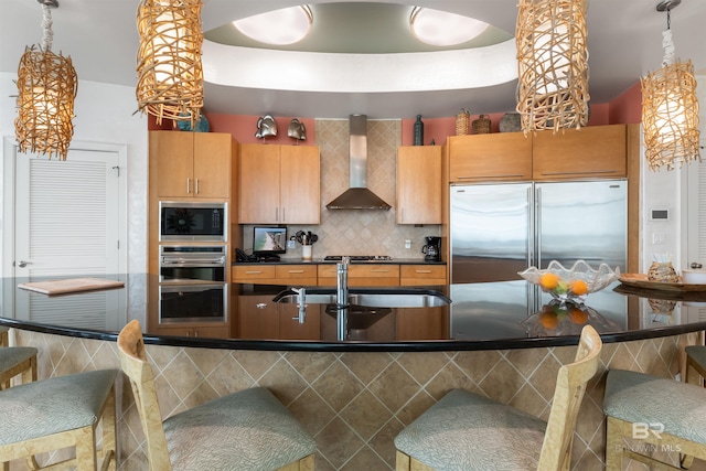 26302 Perdido Beach Blvd Unit D2201, Orange Beach, AL 36561 - kitchen featuring built in appliances, wall chimney exhaust hood, dark countertops, a sink, and a kitchen bar