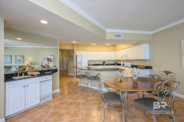 dining room featuring light tile patterned floors, a textured ceiling, ornamental molding, and sink