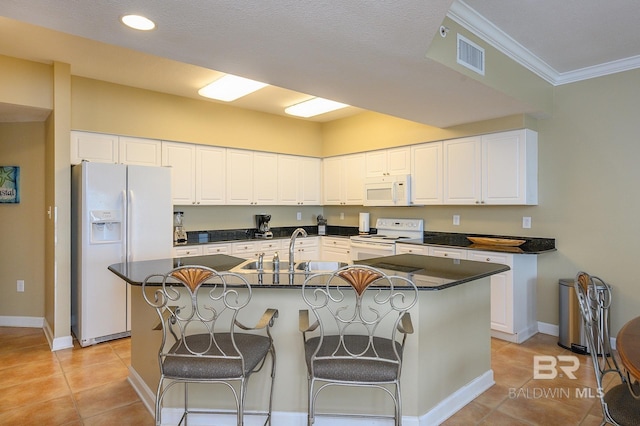 kitchen featuring a kitchen breakfast bar, white appliances, sink, an island with sink, and light tile patterned flooring
