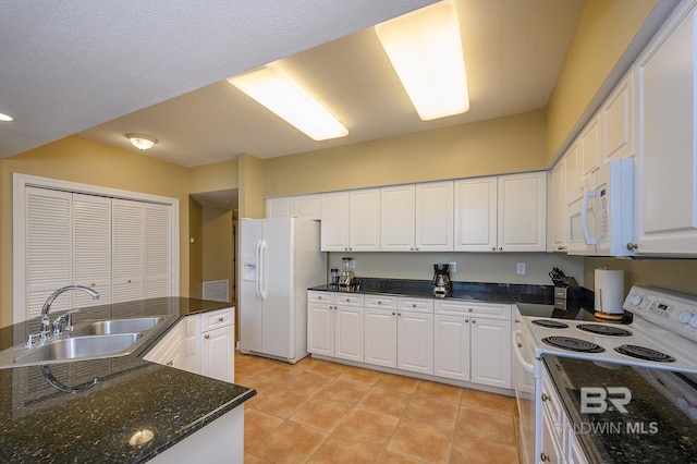 kitchen featuring white cabinetry, sink, dark stone counters, white appliances, and light tile patterned floors