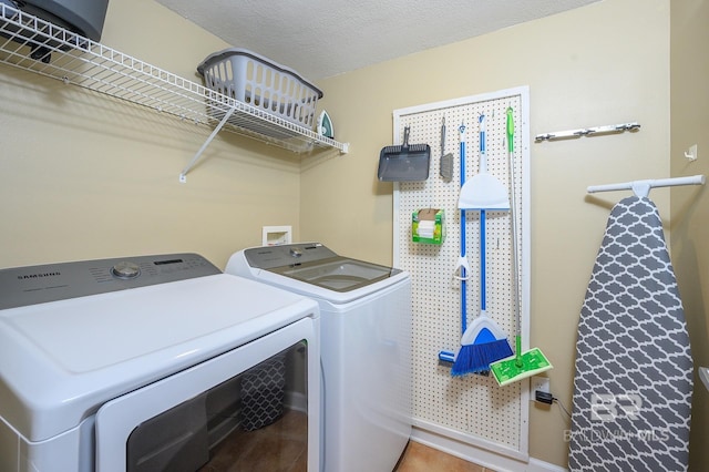 laundry area with independent washer and dryer, a textured ceiling, and tile patterned floors