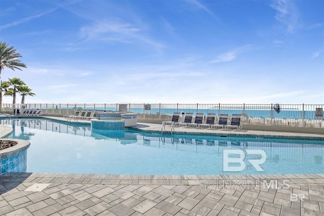 view of swimming pool featuring a water view and a patio