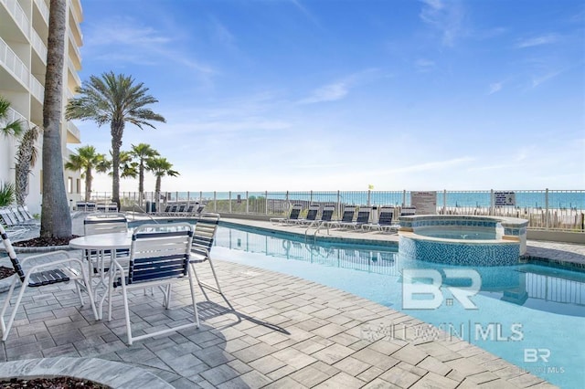 view of swimming pool featuring a water view, a hot tub, and a patio area