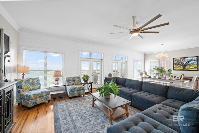 living room with ceiling fan with notable chandelier, wood-type flooring, ornamental molding, and french doors