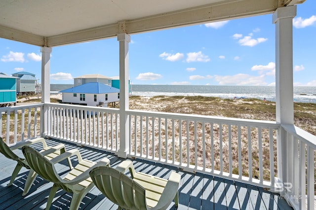 wooden deck with a water view and a view of the beach