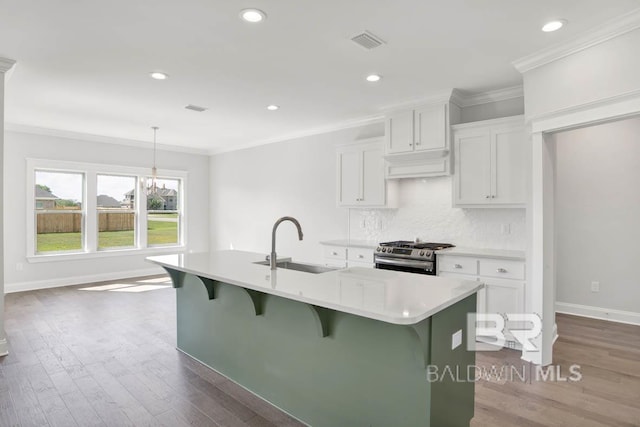 384 Garrison Blvd, Fairhope, AL 36532 - kitchen featuring stainless steel gas range oven, a center island with sink, light countertops, white cabinets, and ornamental molding