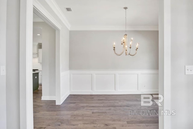 384 Garrison Blvd, Fairhope, AL 36532 - unfurnished dining area featuring ornamental molding, wood finished floors, a chandelier, wainscoting, and a decorative wall