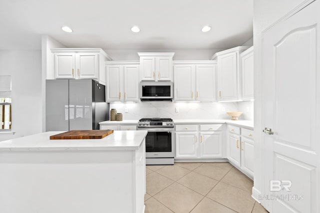 kitchen featuring backsplash, appliances with stainless steel finishes, white cabinets, and light tile floors