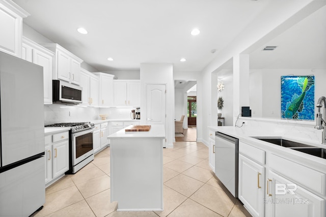 kitchen with white cabinets, a center island, light tile floors, and stainless steel appliances