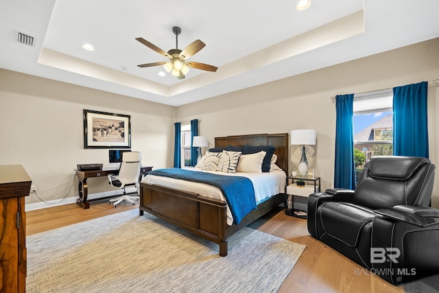 bedroom featuring hardwood / wood-style flooring, ceiling fan, and a raised ceiling