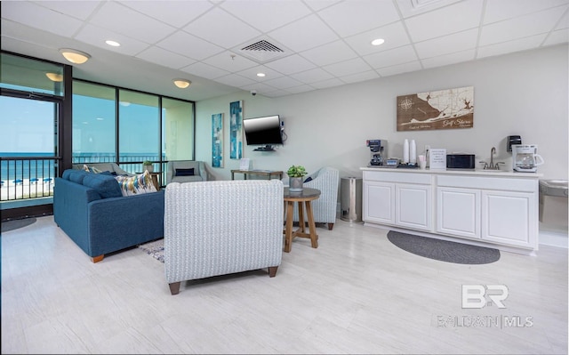 living room with a drop ceiling and expansive windows