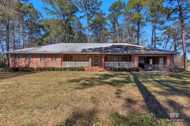 back of property with a lawn, covered porch, brick siding, and a carport
