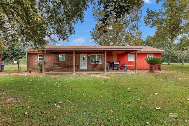 rear view of property with brick siding, a patio area, and a lawn