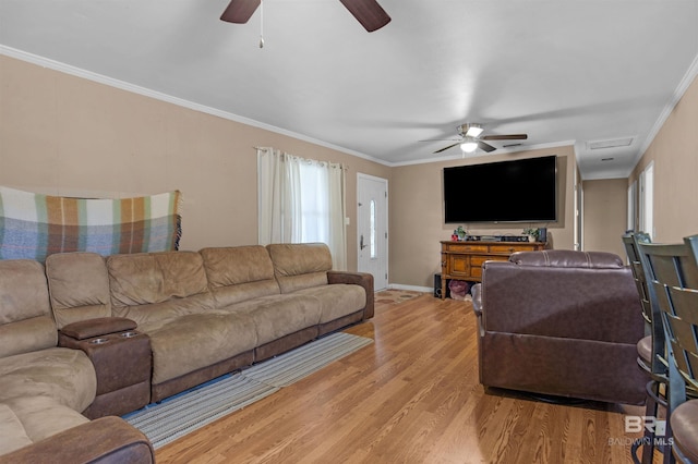 living room featuring visible vents, crown molding, baseboards, light wood-type flooring, and a ceiling fan