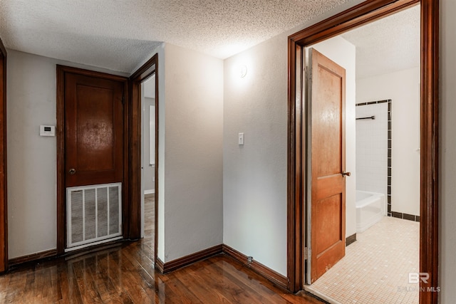 hall with a textured ceiling and dark wood-type flooring