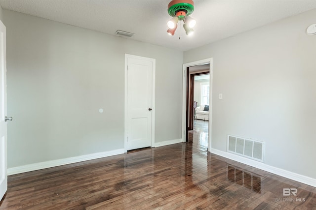 spare room with dark hardwood / wood-style floors, a textured ceiling, and ceiling fan