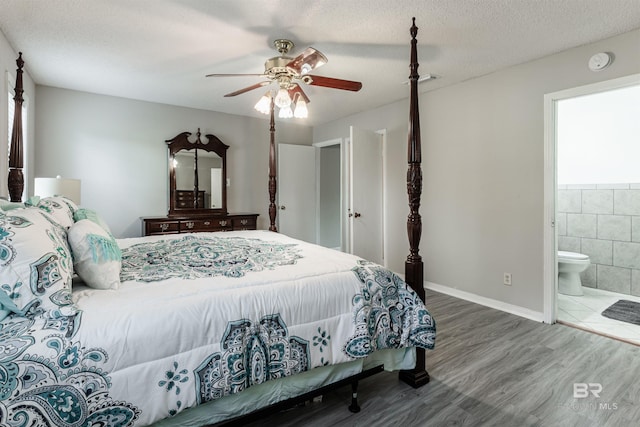 bedroom featuring dark hardwood / wood-style floors, ensuite bath, ceiling fan, a textured ceiling, and tile walls