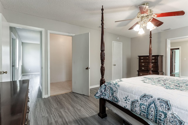 bedroom with dark hardwood / wood-style flooring, ceiling fan, and a textured ceiling