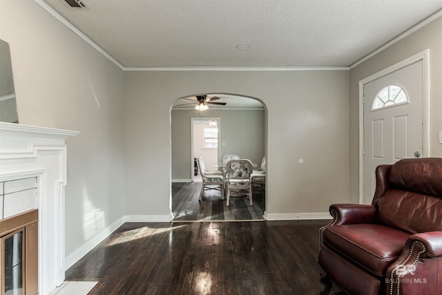 entryway with crown molding, dark hardwood / wood-style flooring, a textured ceiling, and ceiling fan